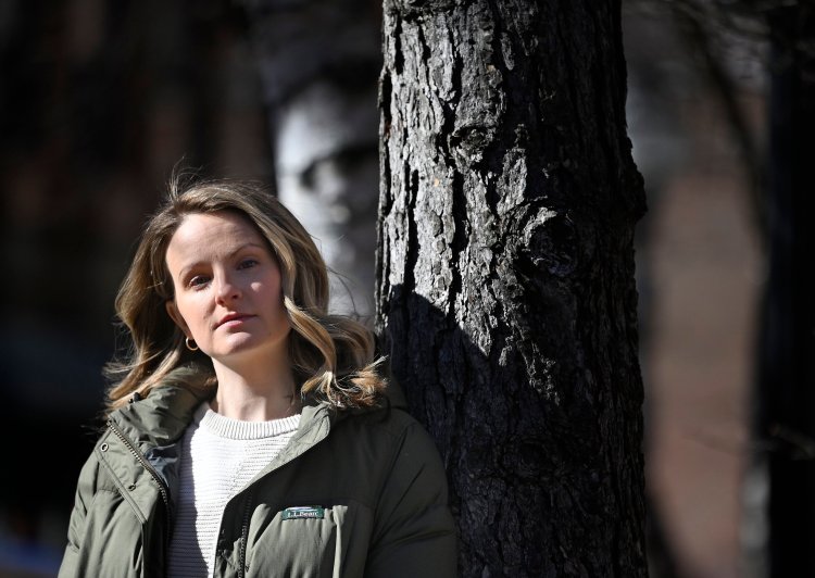 Kylie Low is trying to give a voice to families of cold case victims with her Maine-based podcast, "Dark Downeast." She's pictured here in Portland's Post Office Park where light and shadows on a tree behind formed what looks like a spooky face.