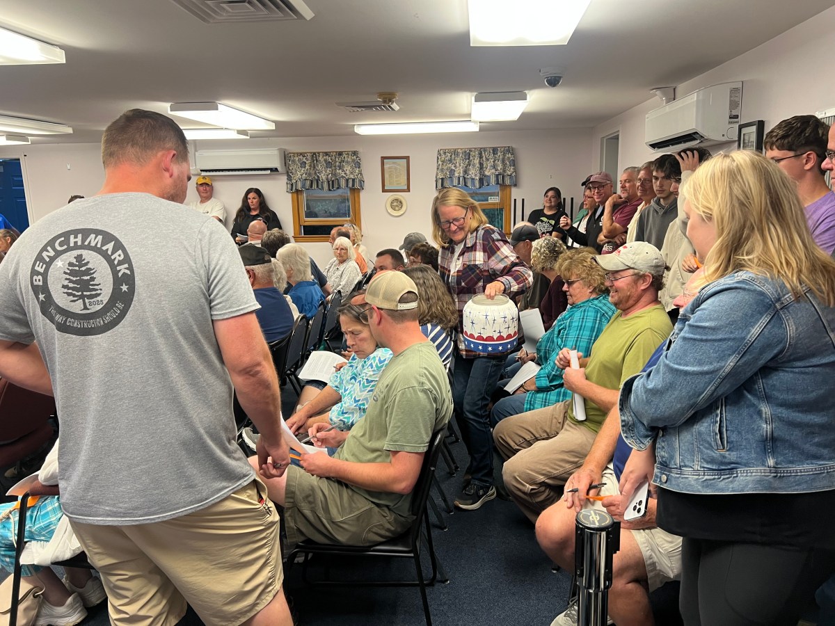 China Deputy Clerk Julie Finley steps through a crowded row of China residents, holding out a plastic bin to collect votes on discontinuing a public easement.